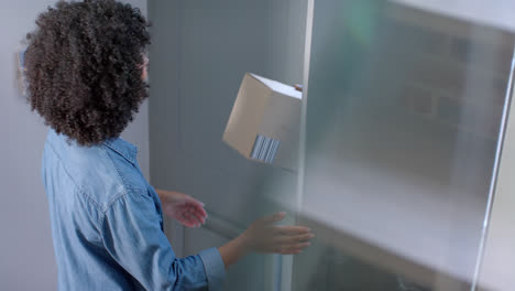 Happy biracial woman receiving parcel at home, slow motion