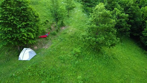 chilling on hammock near waterproof tent in the forest drone circle shot