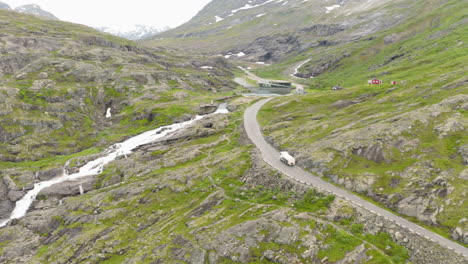 vehicle traveling in narrow road by the rocky slopes of trollstigen, norway - aerial shot