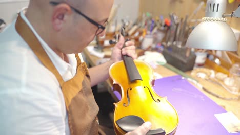 luthier installing sound post to violin