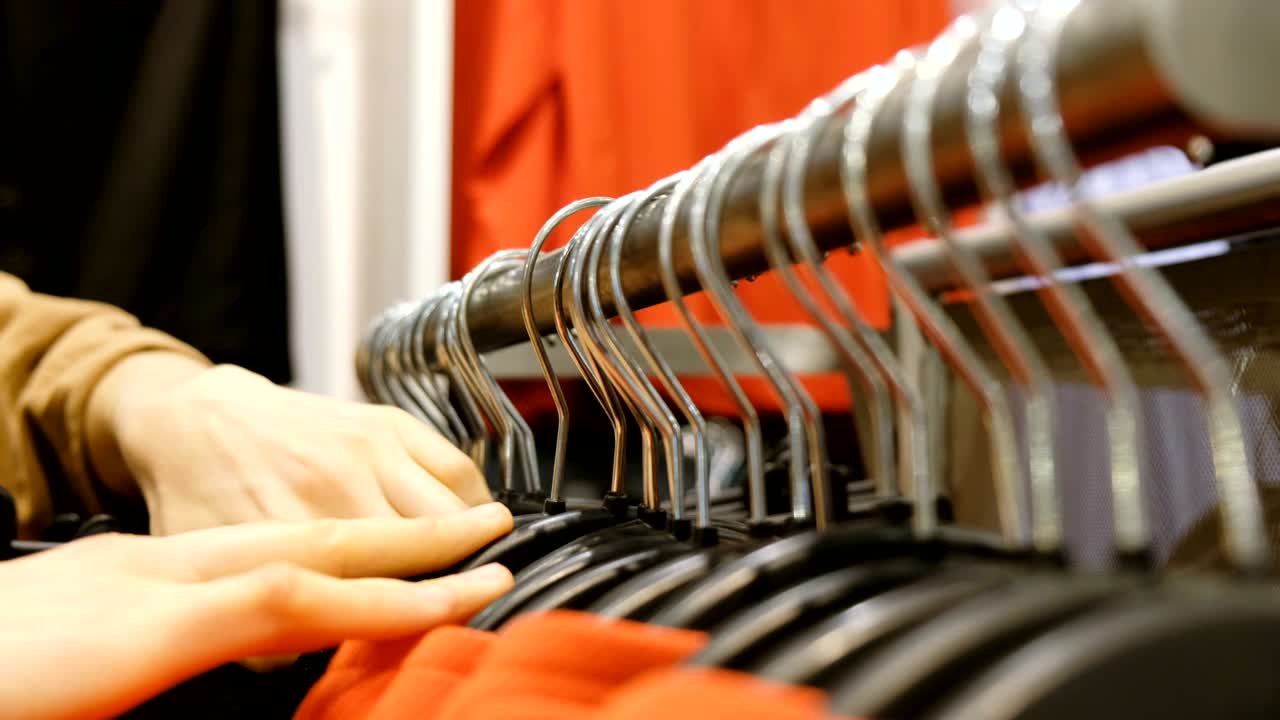 mujer toma ropa en una percha en una tienda, primer plano