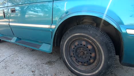 Wheel-and-hubcap-of-a-blue-van-in-the-driveway-in-the-daytime