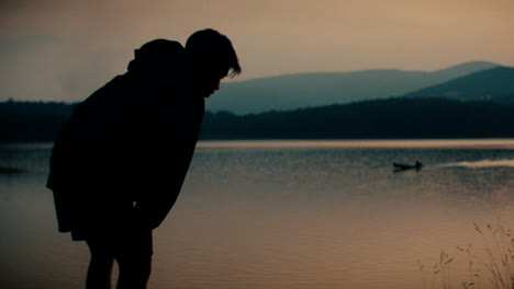 silhouette of person by lakeside at sunset