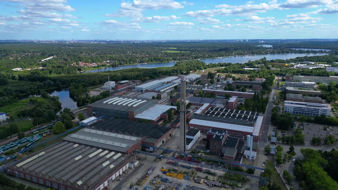 Hennigsdorf industrial area with modern offices, old factory buildings and chimneys under blue sky. Nice aerial view flight panorama overview drone