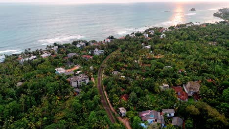 stunning drone aerial footage of weligama bay at sunset, showcasing golden skies reflecting over the calm indian ocean.