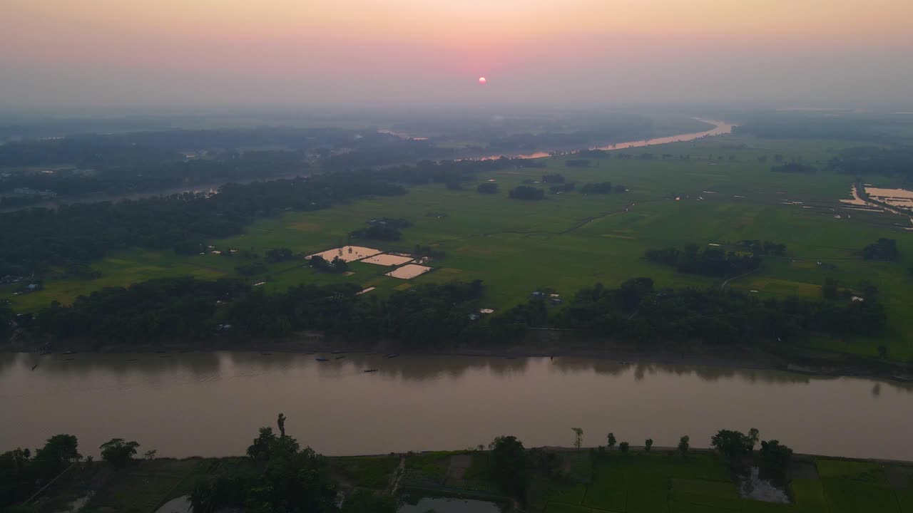 Una splendida alba su un paesaggio agricolo panoramico con un fiume che scorre attraverso la campagna vicino a un villaggio, catturando l'essenza della vita rurale