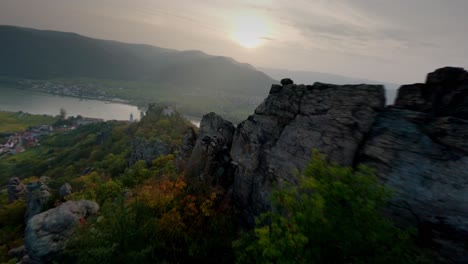 adventurous descending fpv shot capturing mighty stone formations, dürnstein, and its historic ruin surrounded by nature