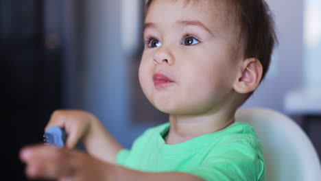 beautiful caucasian baby eating well from fork. cute toddler having meals at the high chair. close up.