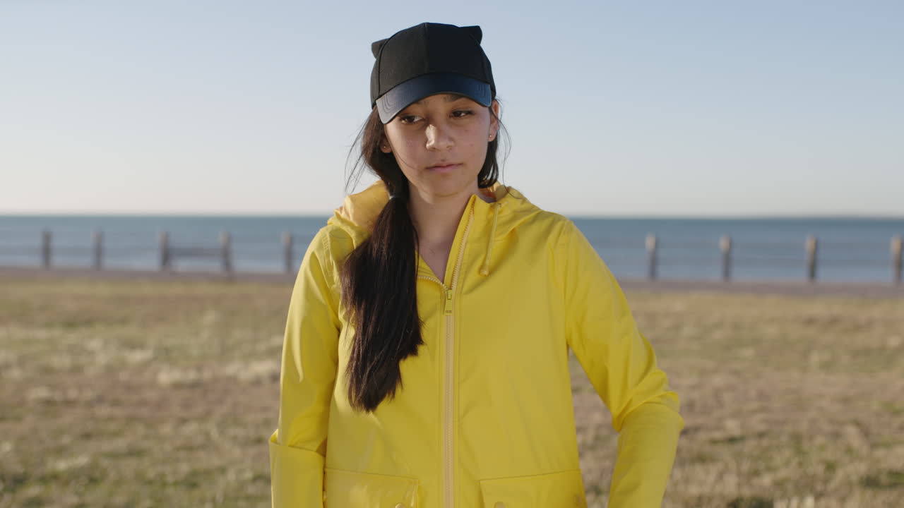 혼혈 십대 소녀의 초상화 문자 메시지 브라우징 스마트 폰 기술을 사용하여 카메라에 행복하게 미소 짓고  ⁇ 은 해변 공원을 즐기고