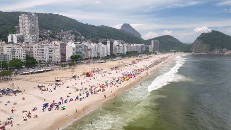 drone flight along iconic copacabana stretch of white beach with beachgoers, rio