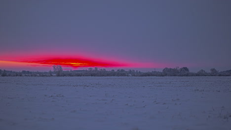 Zeitrafferaufnahme-Eines-Schneebedeckten-Feldes-In-Der-Natur-Und-Rot-Gefärbtes-Sonnenlicht-Zwischen-Dichten-Wolken-Am-Himmel