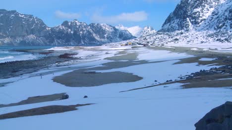 las olas ruedan hacia una hermosa playa cubierta de nieve en medio de fiordos al norte del círculo polar ártico en las islas lofoten noruega 1