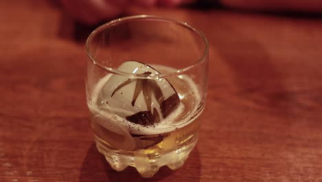 hand stirring a drink with ice in glass