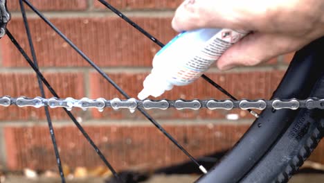 Close-up-of-a-mechanic-placing-lubricant-on-a-freshly-cleaned-bicycle-chain-as-a-part-of-routine-maintenance