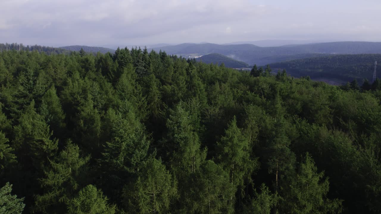Vista aerea cinematografica in 4K con drone di una fitta foresta circondata da un paesaggio montuoso nella comunità di Weibersbrunn, Germania