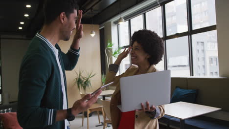 diversas personas de negocios de pie usando una computadora portátil y una tableta digital en una oficina moderna