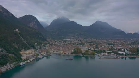 Toma-Aérea-Del-Barco-De-Pasajeros-Que-Sale-Del-Puerto-Deportivo-De-Riva-Del-Garda,-Italia