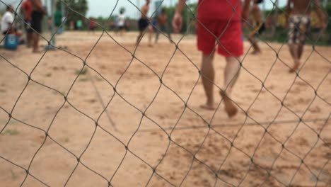 primer plano gente jugando voleibol detrás de una cerca de metal de cadena