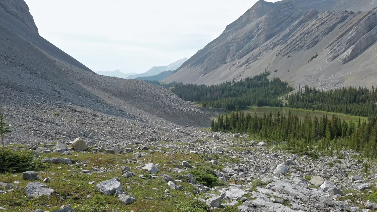 Panoramica di un laghetto di montagna in una valle con bagliore solare sulle Montagne Rocciose, Kananaskis, Alberta, Canada.