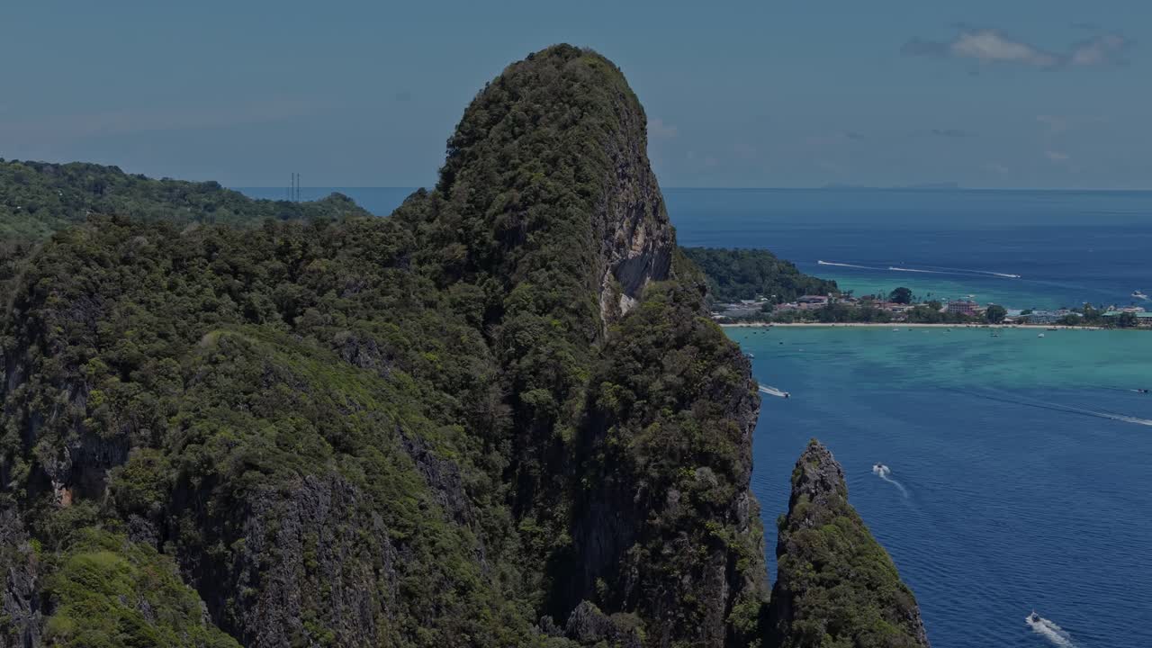 Cinematic drone semi orbit encircling majestic coastal cliffs and deep blue ocean on a clear tropical day in April on Phi Phi Islands, Thailand.