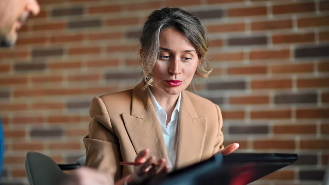 Man and woman discussing plans on a screen at the table, in an office