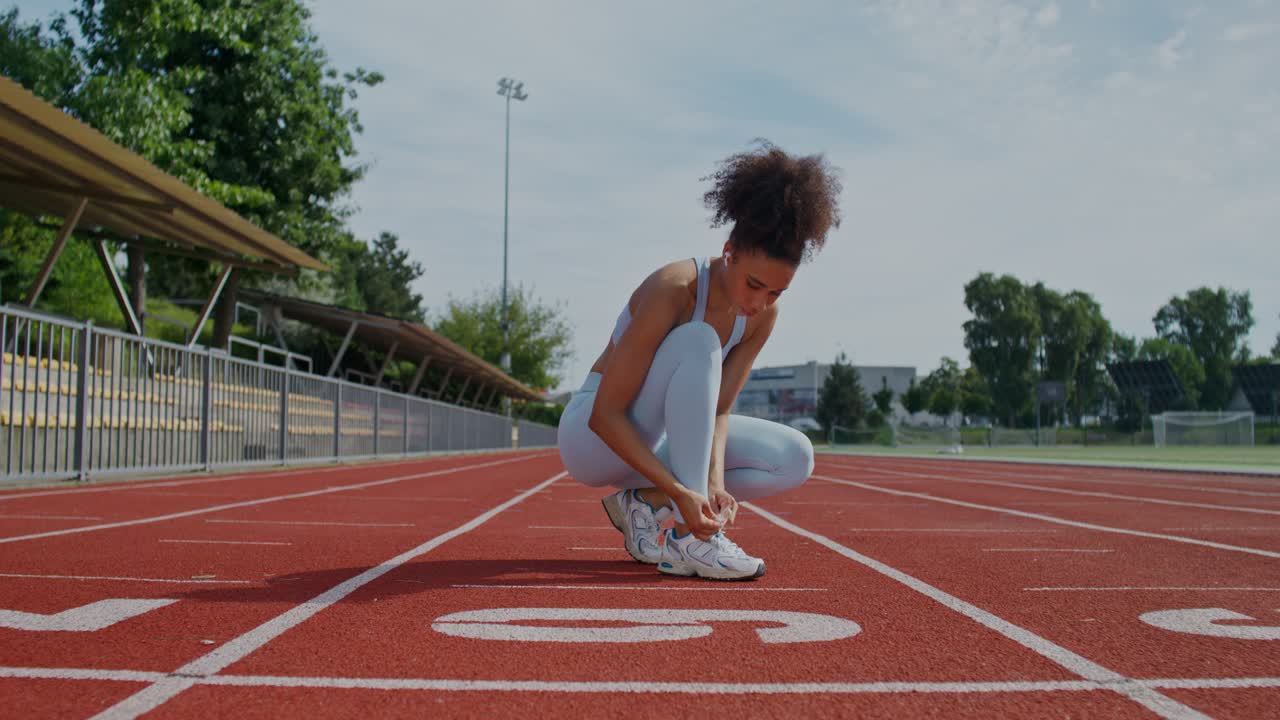 mujer atando zapatos en una pista de atletismo