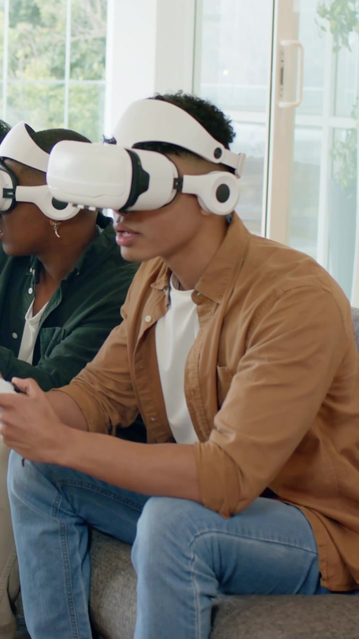 Video verticale: Uomo in camicia beige preme pulsanti, si muove, gioca alla VR a casa con visore e controller.