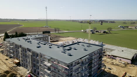 fly towards building site with high crane against grassy landscape in lubawa, poland