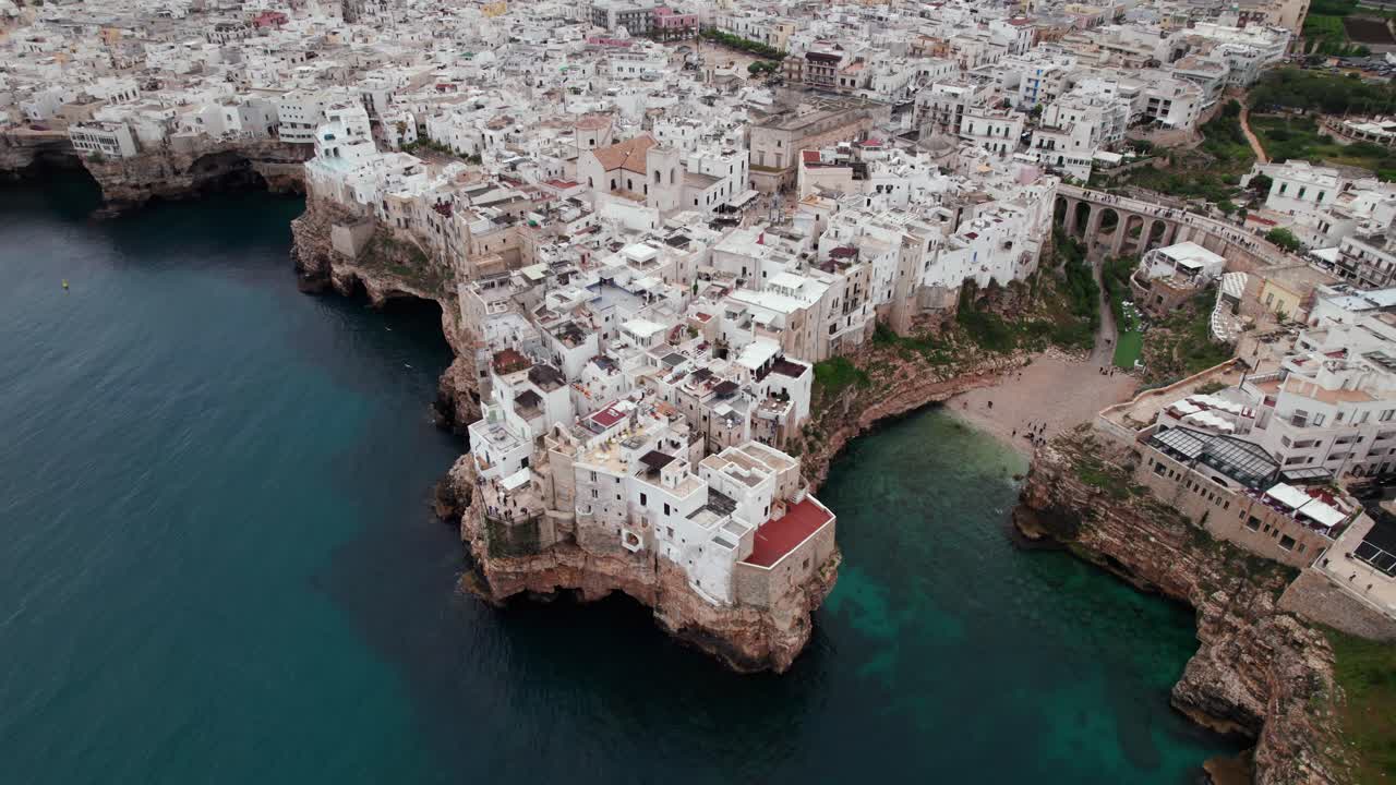Aerial orbit view of Polignano a mare city buildings on rocky coast, Puglia, Italy