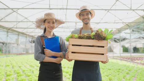 smiling farmers holding fresh produce in greenhouse