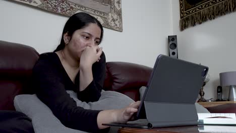 Woman-on-couch-absorbed-in-tablet-content,-cozy-home-interior,-casual-leisure-time,-low-angle-shot