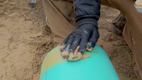 construction worker spreading pipe lube - grease on the end of a sewer pipe in preparation for assembly