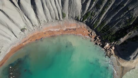 Top-Down-View-Of-A-Tropical-Sandy-Beach-With-Clear-Turquoise-Water,-Qarraba-Bay-And-Clay-Cliffs,-Malta