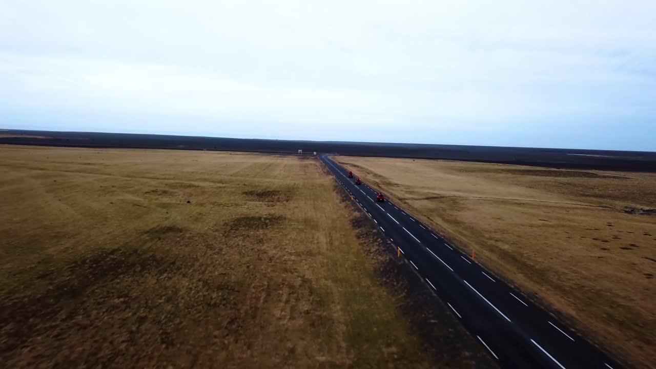 vista aérea de quads rojos acelerando en una carretera recta vacía a través de las tierras altas de islandia