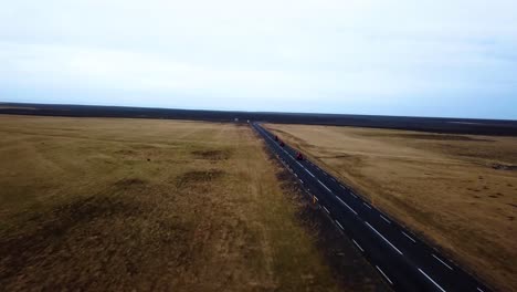 Vista-Aérea-De-Quads-Rojos-Acelerando-En-Una-Carretera-Recta-Vacía-A-Través-De-Las-Tierras-Altas-De-Islandia