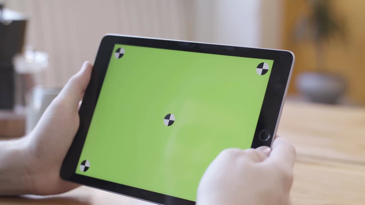 persona que sostiene una tableta con una pantalla verde