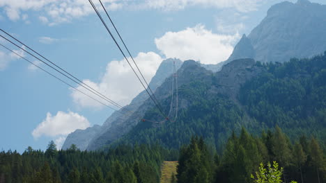 Tram-cable-car-lines-swoop-over-tree-tops-in-valley-of-Zugspitze,-Germany