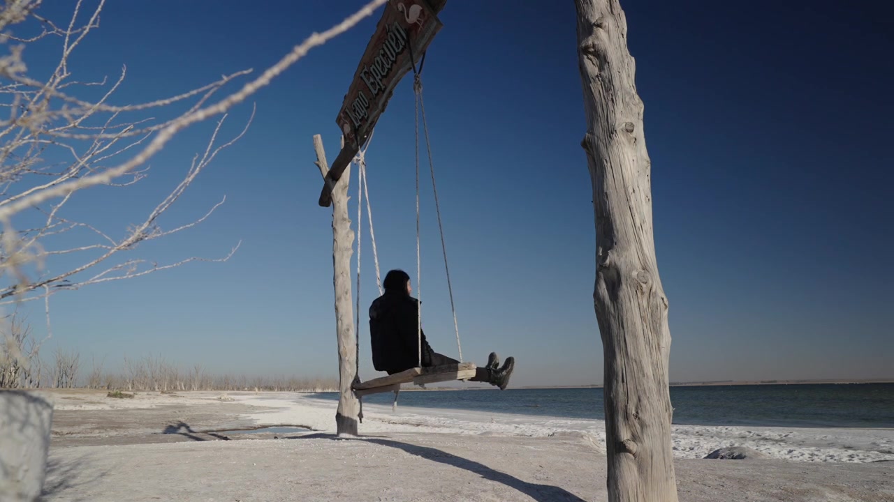 Donna che si dondola su un'altalena di legno tra le rovine abbandonate di Villa Epecuen, Argentina.