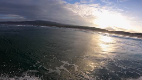 el sol se pone sobre la superficie del océano, el punto de vista submarino con algunas nubes y el surf al mismo tiempo
