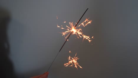 young woman holding a sparkler against grey background