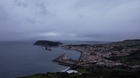 Toma-Aérea-Nocturna-De-Horta-Con-Un-Faro-Iluminado-En-La-Bahía.