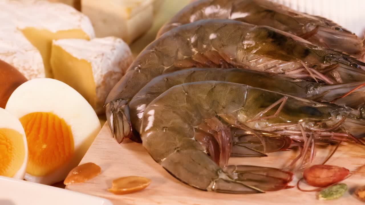 A variety of protein sources including eggs, shrimp, chicken, and beef displayed on a wooden board.