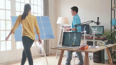 asian man and woman discuss work with solar cell panel and laptop computer showing wind turbine