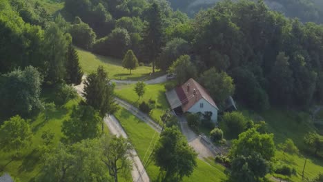 small countryside farm up in hills between green meadows and forest breeding cows