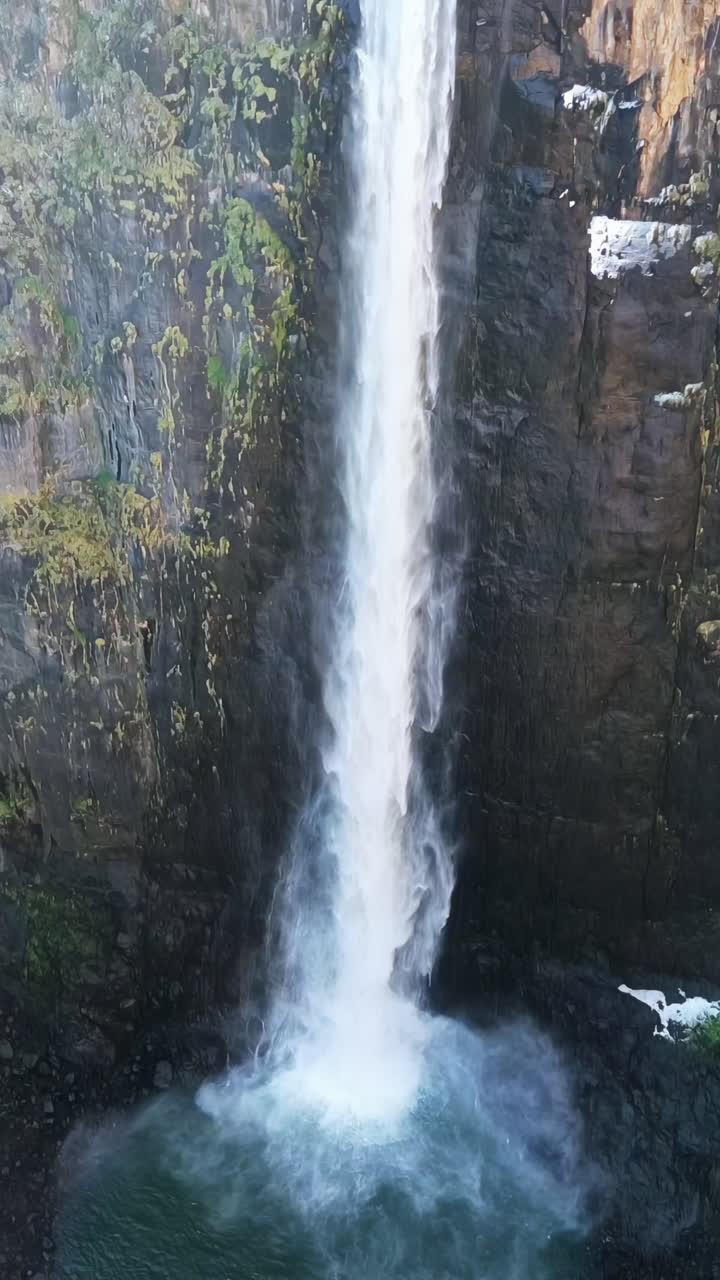 Vista aerea con drone delle Cascate Maletsunyane che si gettano in un profondo canyon negli altipiani del Lesotho, circondate da scogliere frastagliate e vasti paesaggi montani. Verticale