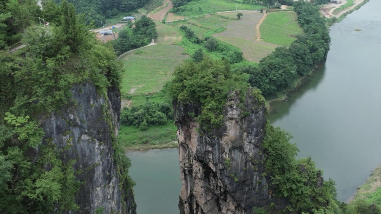 Quang cảnh từ trên cao bằng drone về những khối đá tự nhiên sừng sững vươn lên trên dòng sông uốn lượn và những cánh đồng nông thôn ở vùng nông thôn Hàn Quốc. Một phong cảnh hữu tình kết hợp những vách đá hùng vĩ, những khu rừng tươi tốt, nông nghiệp