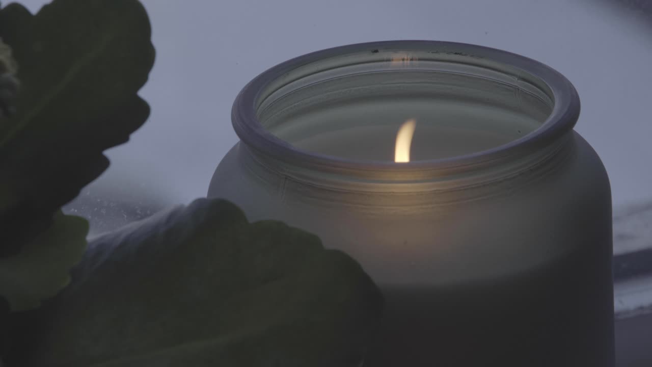 Suggestive lit candle in glass vase. Close-up