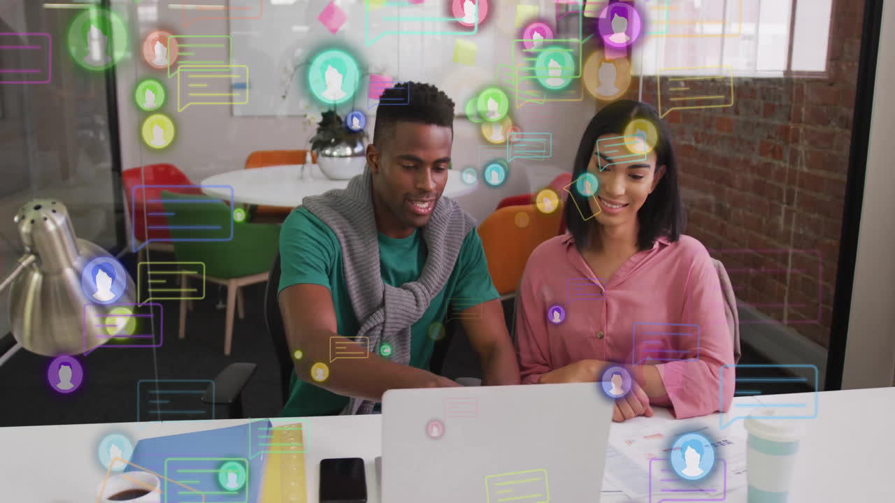 Collaborating at desk, colleagues surrounded by animation of social media icons
