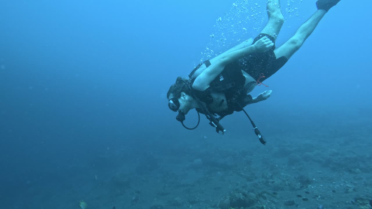 buzo masculino bajando al fondo del mar, buceo en el agua azul del océano