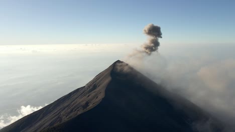 aerial drone orbit of volcano acatenango with clouds rolling over its slopes, serene atmosphere, dark erupting smoke rises